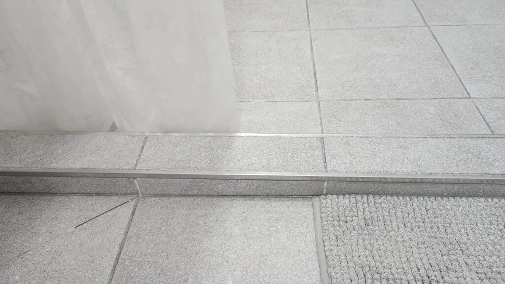 물흐름 방지턱과 샤워커튼을 배치한 미니멀 욕실 인테리어